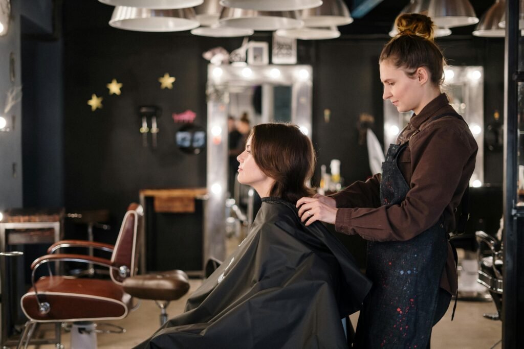 A hairstylist trims a client's hair in a modern salon setting, capturing a moment of focus.