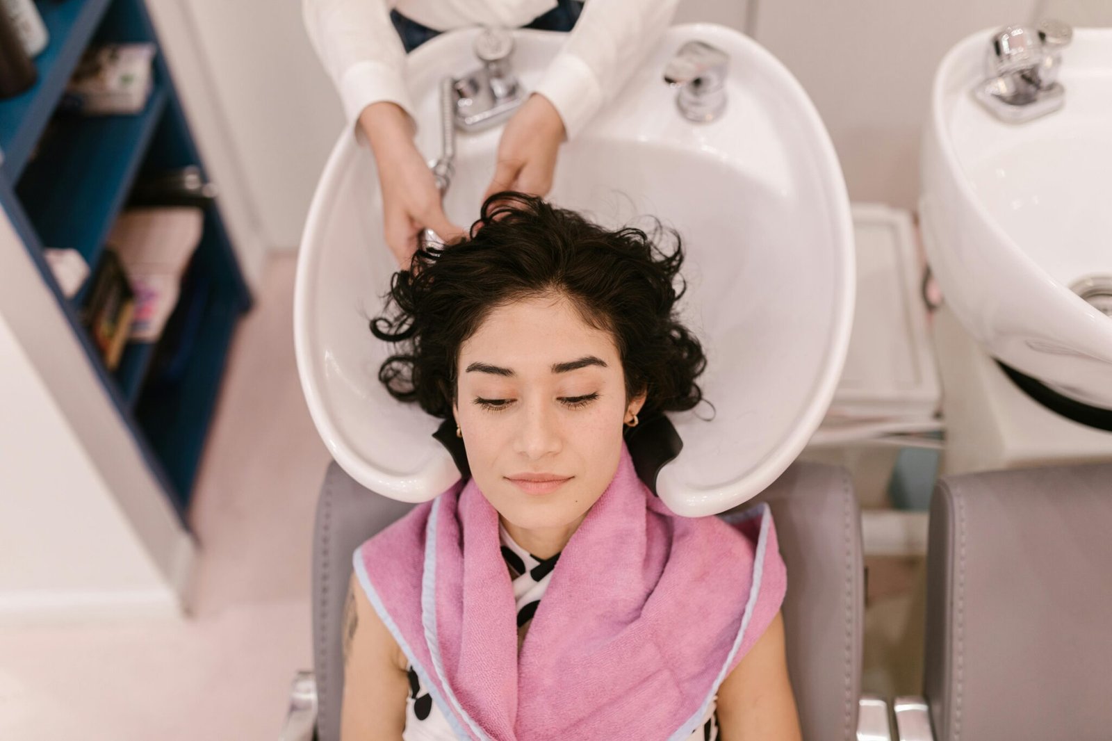 A woman enjoys a relaxing hair wash at a modern hair salon, focusing on self-care.